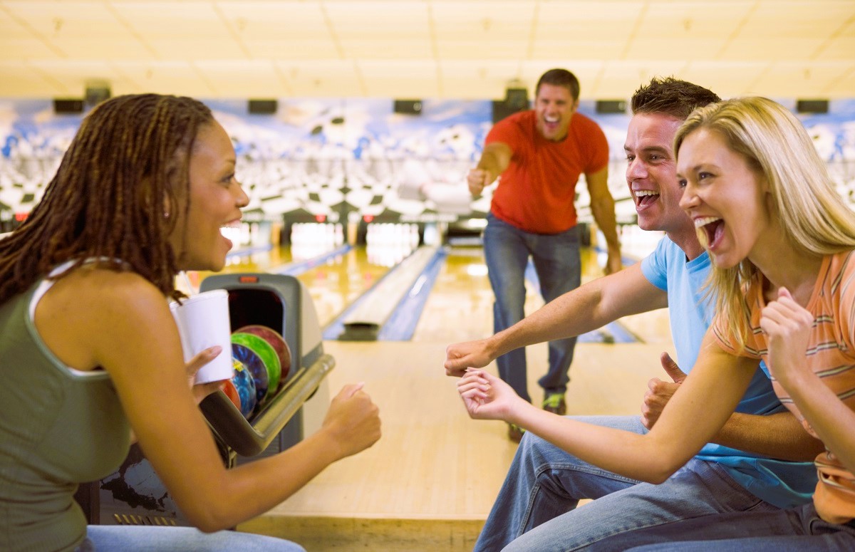 Four young adults cheering in a bowling alley